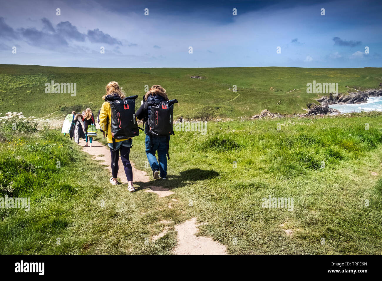 Holidaymakers walking along a footpath leading down to Polly Porth Joke in Newquay in Cornwall. Stock Photo