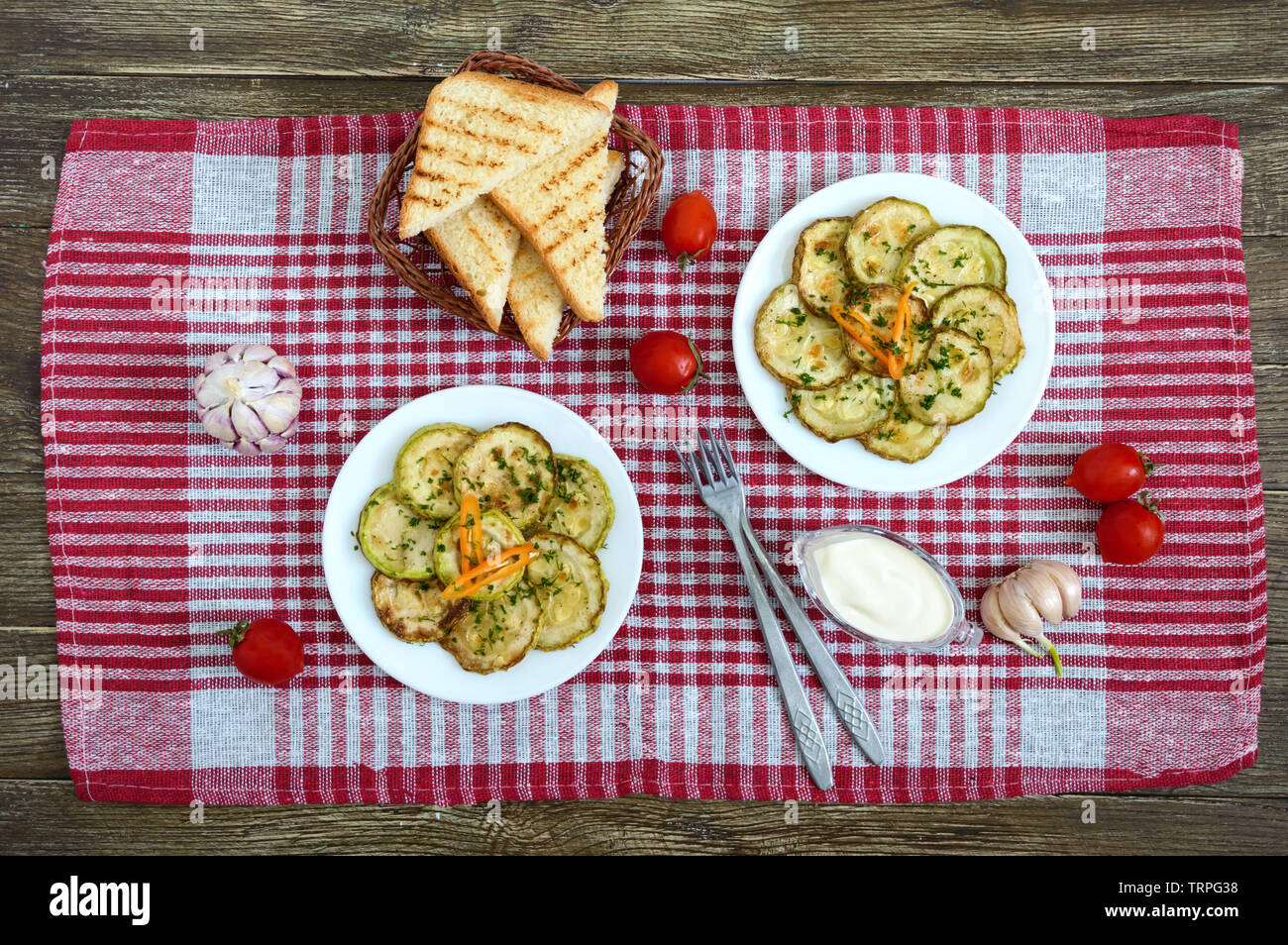 Tasty fried zucchini slices on a plate with sauce on a wooden table. Picnic snack. Rustic style. Top view, flat lay. Stock Photo