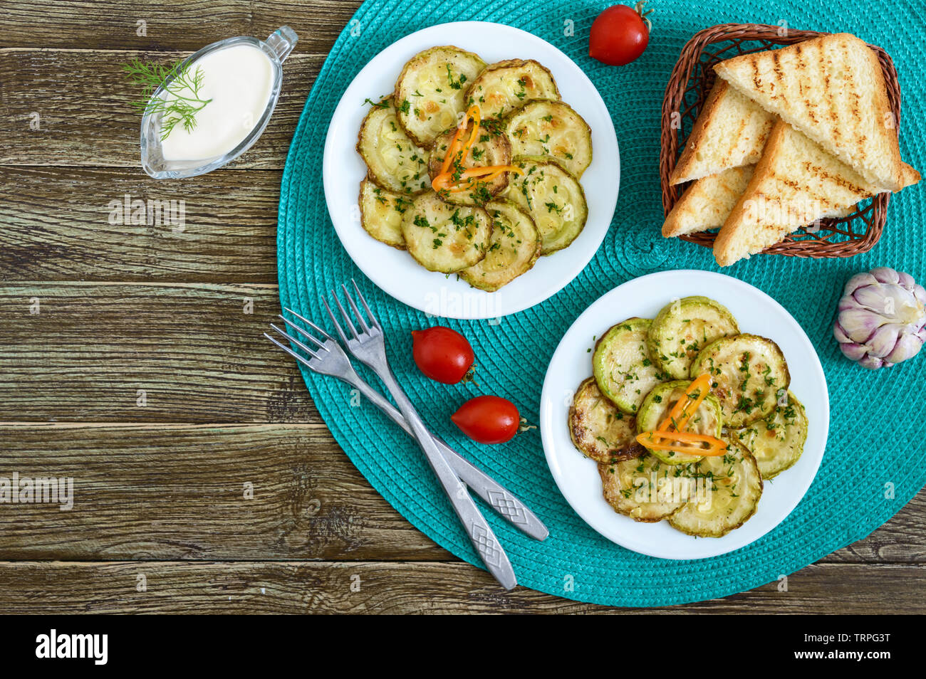 Tasty fried zucchini slices on a plate with sauce on a wooden table. Picnic snack. Rustic style. Top view, flat lay. Stock Photo