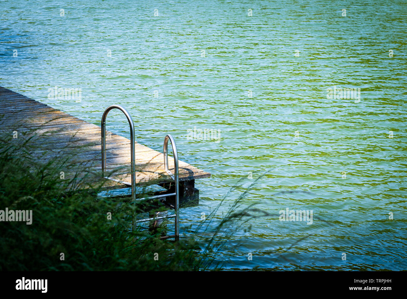 Old wooden pier with metal ladder into the lake Stock Photo