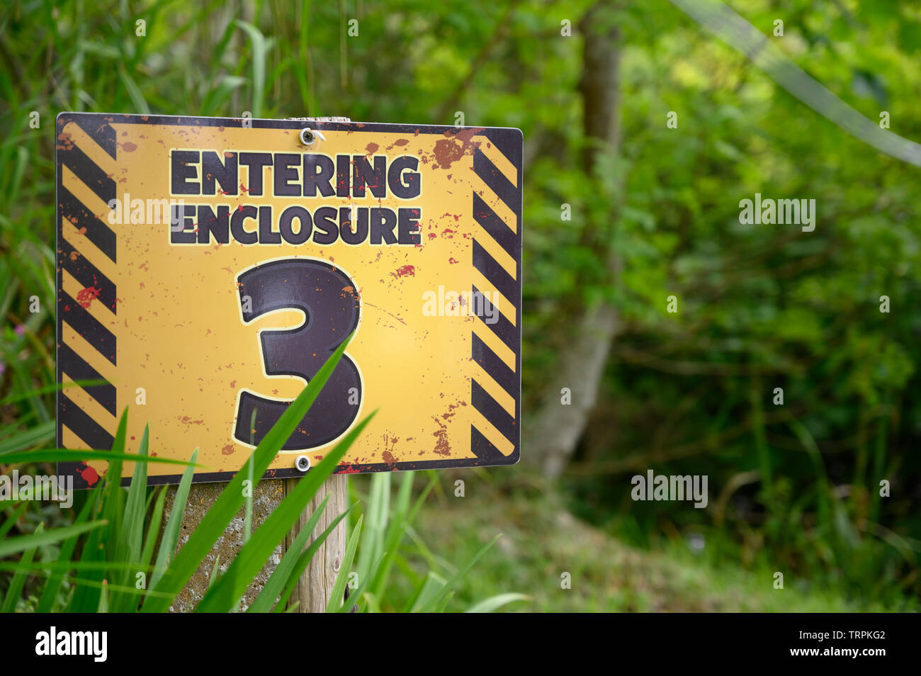 Entering enclosure three sign in theme park forest Stock Photo