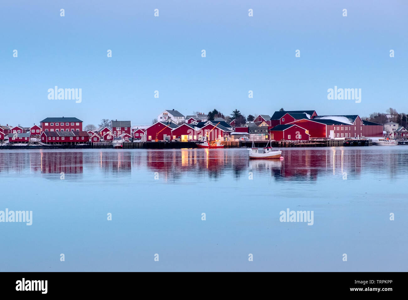 Red fishing warehouse with fishing boat reflection on coastline at evening Stock Photo