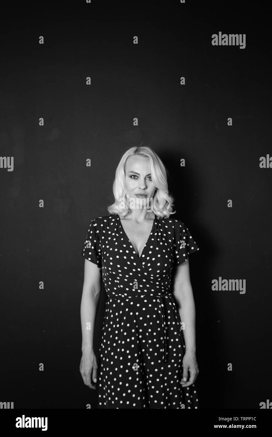 Studio portrait of beautiful blonde woman in a black dress against ...