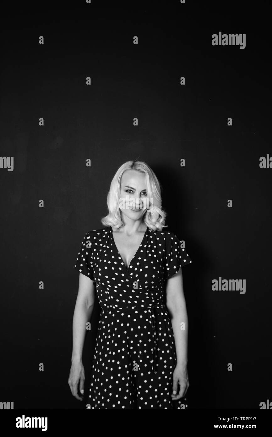 Studio portrait of beautiful blonde woman in a black dress against ...