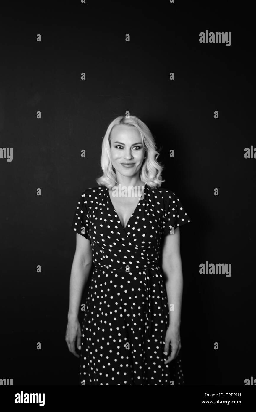 Studio portrait of beautiful blonde woman in a black dress against ...