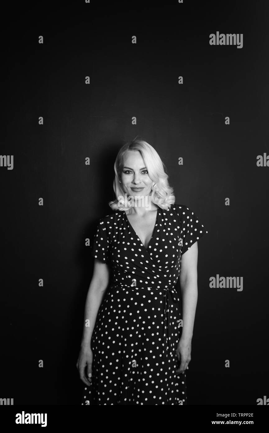 Studio portrait of beautiful blonde woman in a black dress against ...