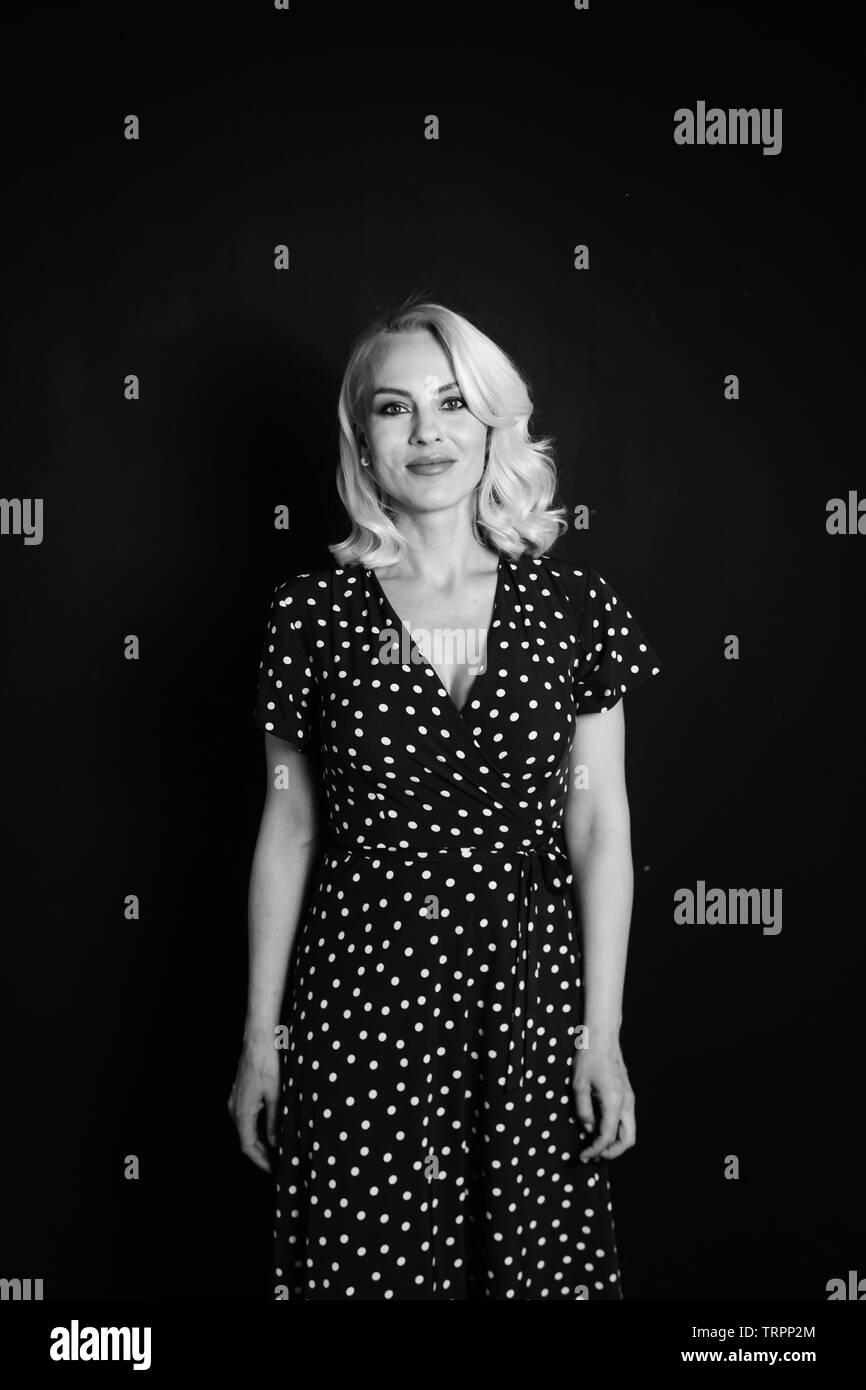Studio portrait of beautiful blonde woman in a black dress against ...