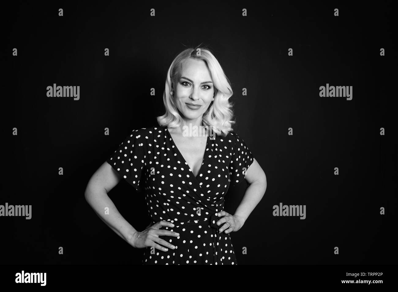Studio portrait of beautiful blonde woman in a black dress against ...