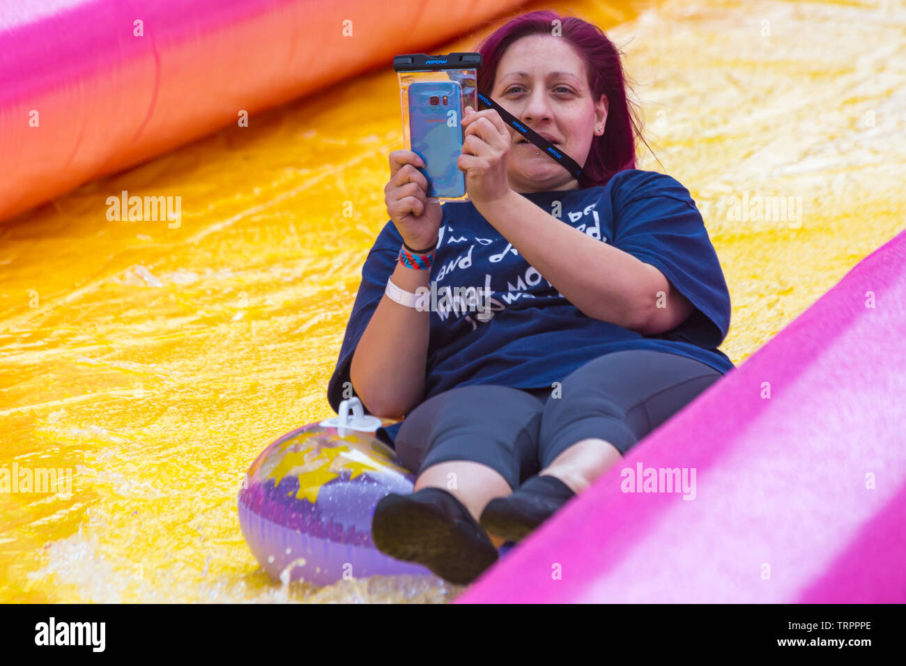 Woman on inflatable ring having fun and taking selfie on giant waterslide, water slide, at Bournemouth, Dorset UK in June Stock Photo