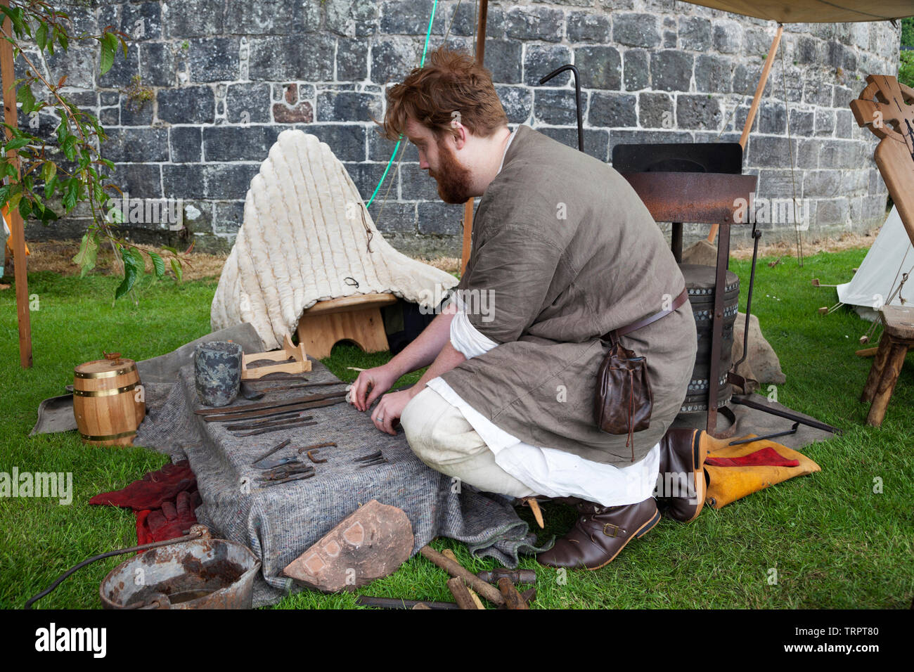 Reenactor of the early renaissance laying out metal working tools at the Rock of Ages festival, Dumbarton Castle, Scotland Stock Photo
