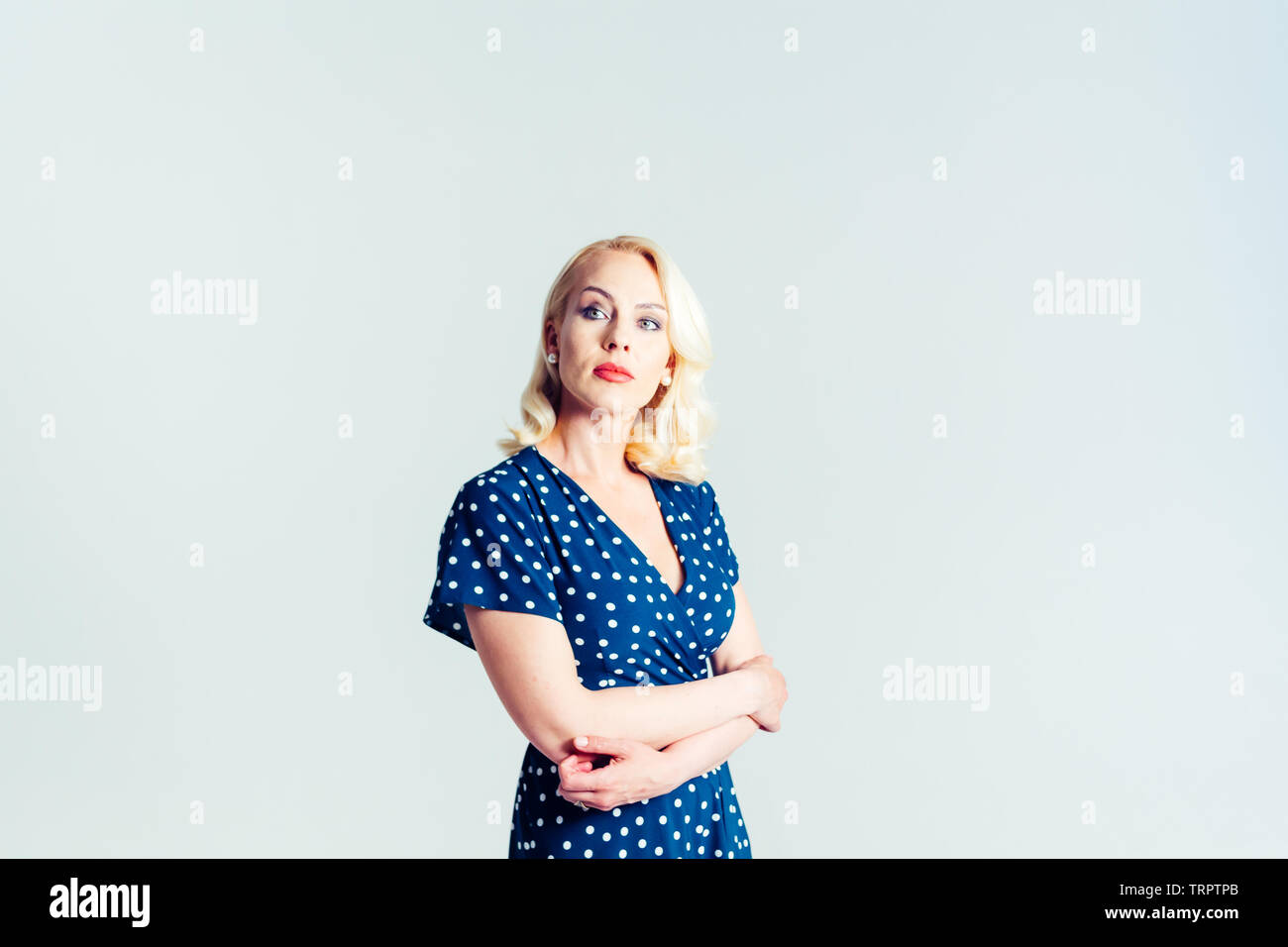 Studio portrait of beautiful blonde woman in a dark blue dress against ...