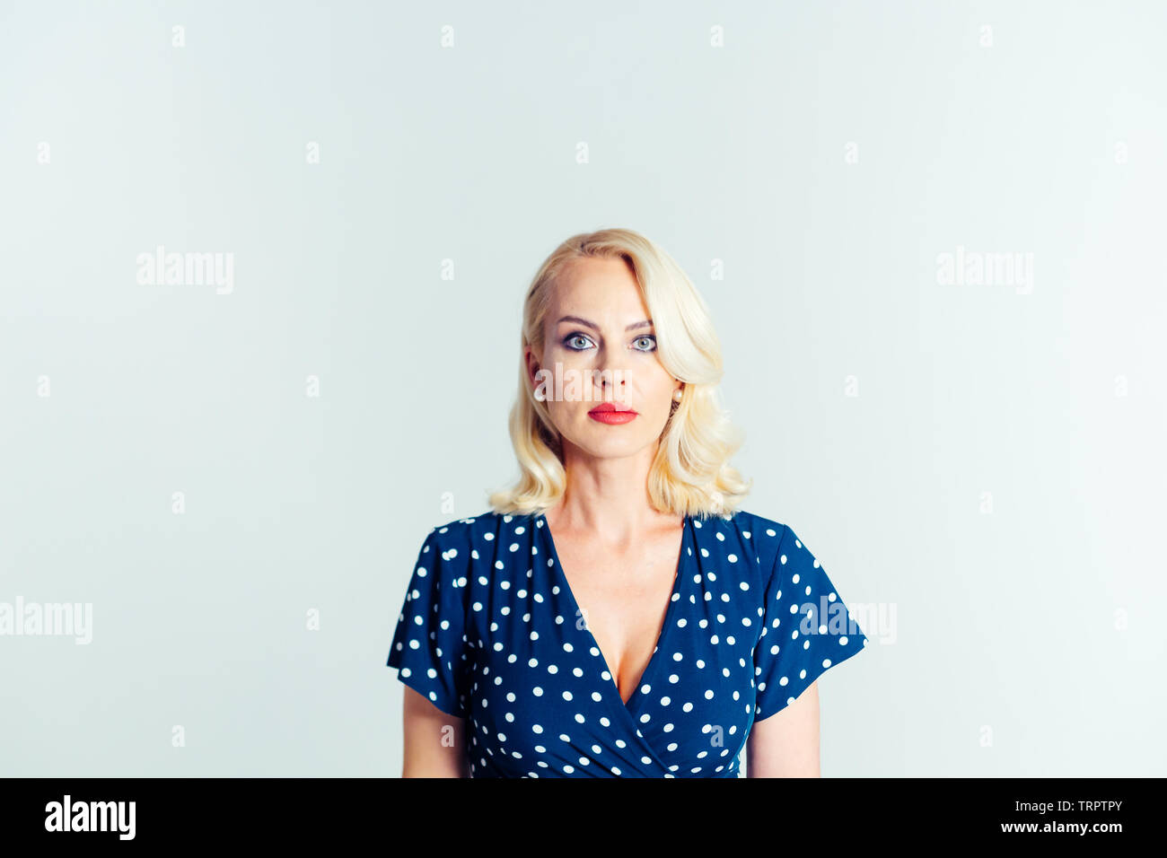 Studio portrait of beautiful blonde woman in a dark blue dress against ...