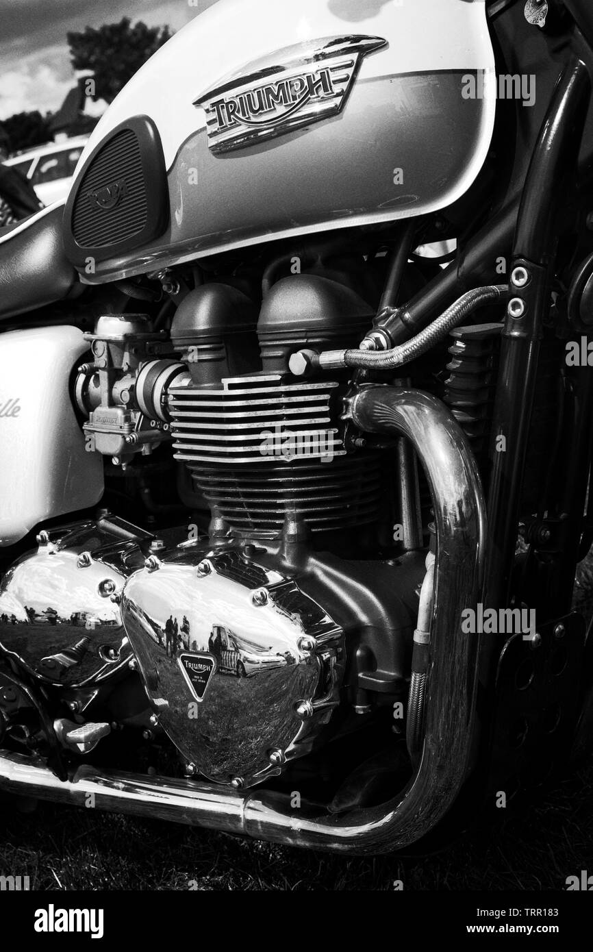 Engine and fuel tank close up of a classic Triumph Bonneville motorcycle showing cooling fins, exhausts and brightwork in black and white. Stock Photo