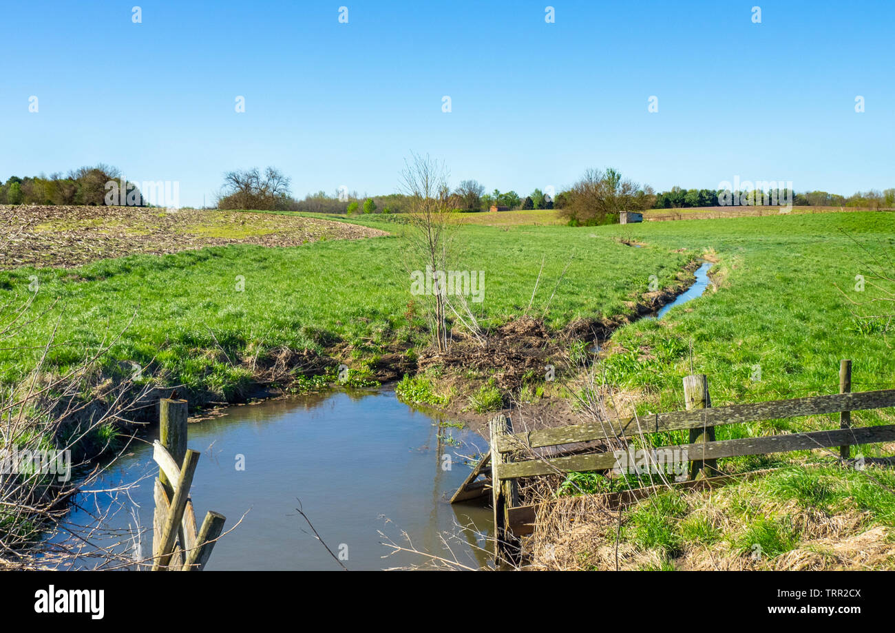 Wooden fence between paddocks, irrigation pond in rural midwest