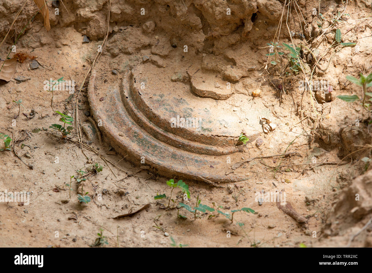 anti tank mine partly buried in the ground Stock Photo
