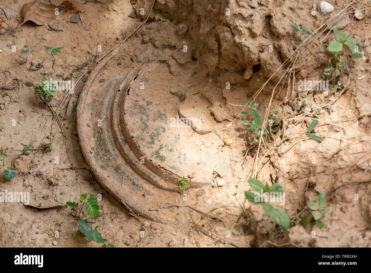 anti tank mine partly buried in the ground Stock Photo