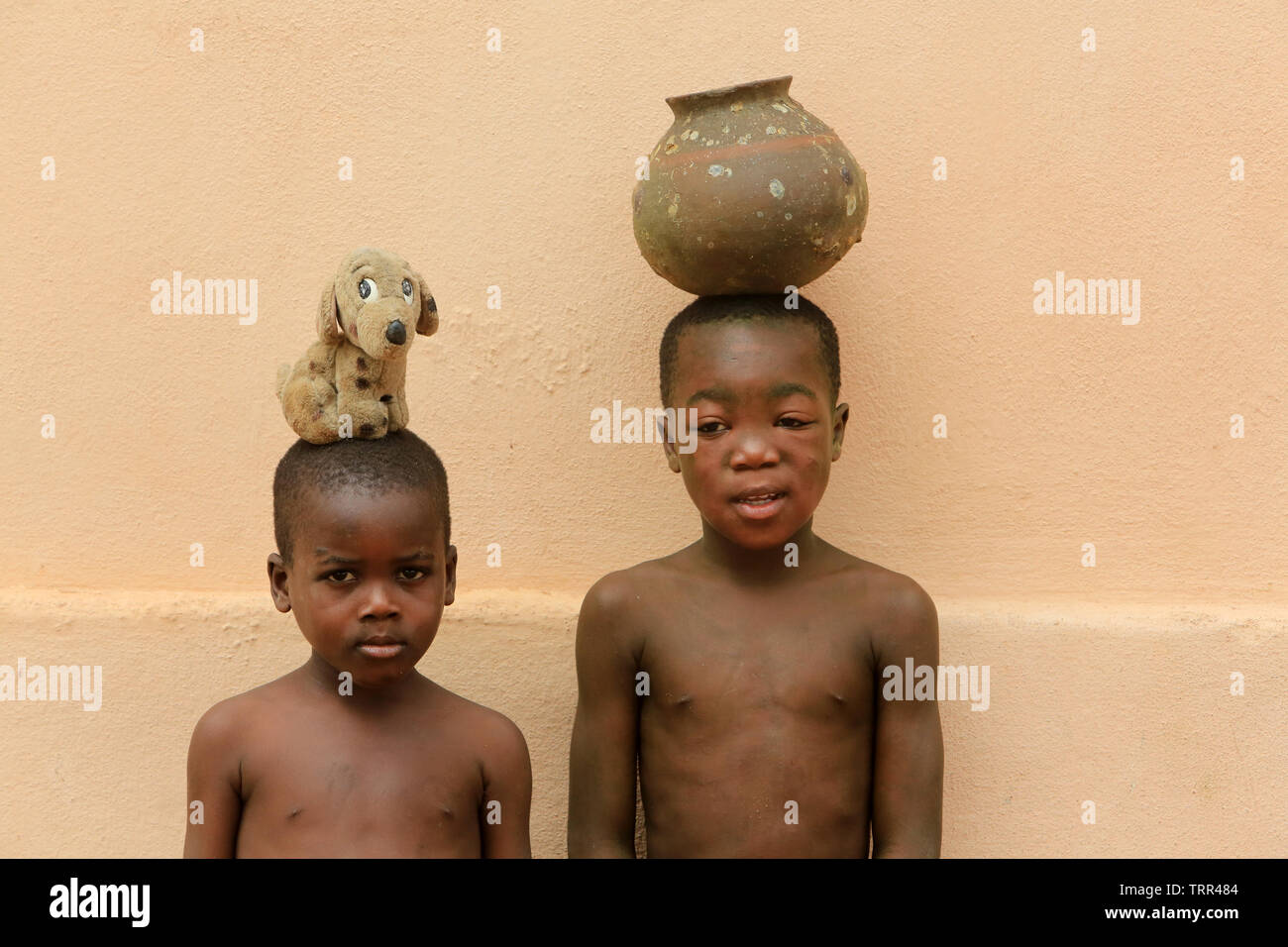 Enfants togolais portant une vasque et une peluche sur la tête. Togoville. Togo. Afrique de l'Ouest. Stock Photo