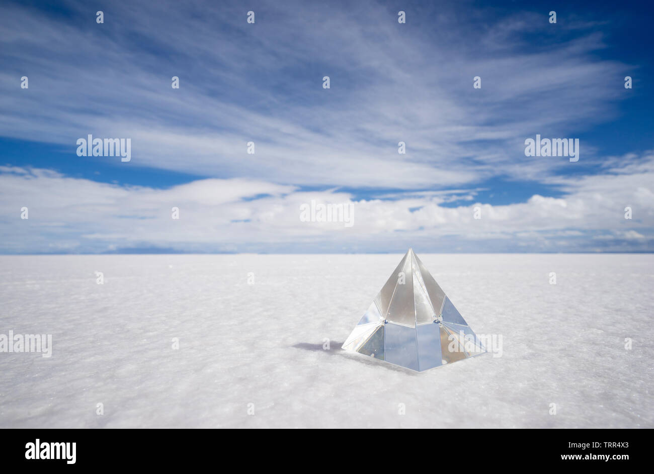 a crystal pyramid stands in a dry and sunny salt desert Stock Photo