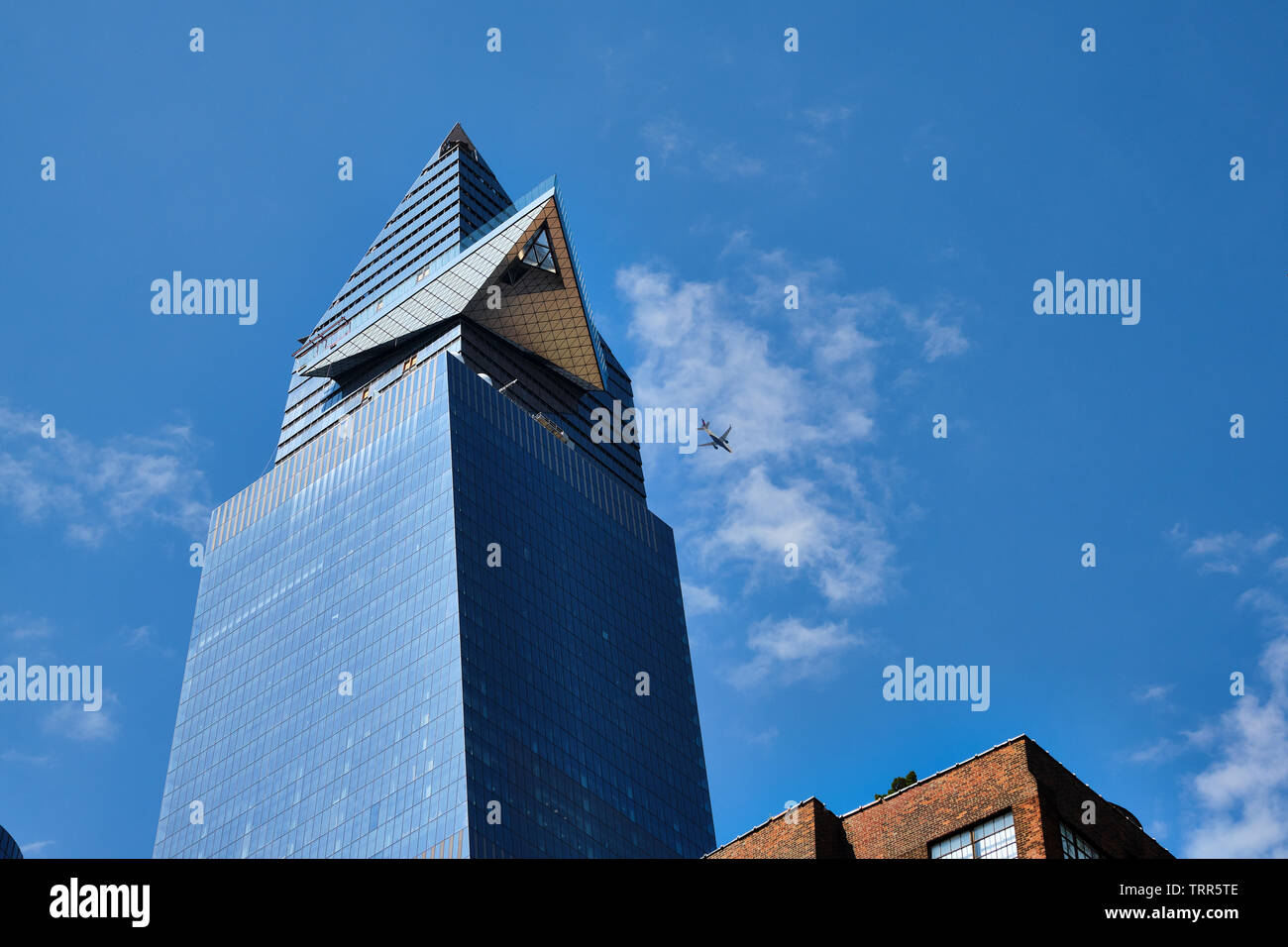 Pictured is a skyscraper building with an overhead airplane passing. New York City, USA. Stock Photo