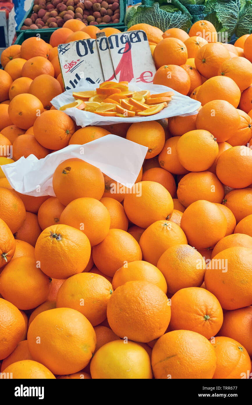 Tangerines for sale at a market with some pieces on a plate Stock Photo