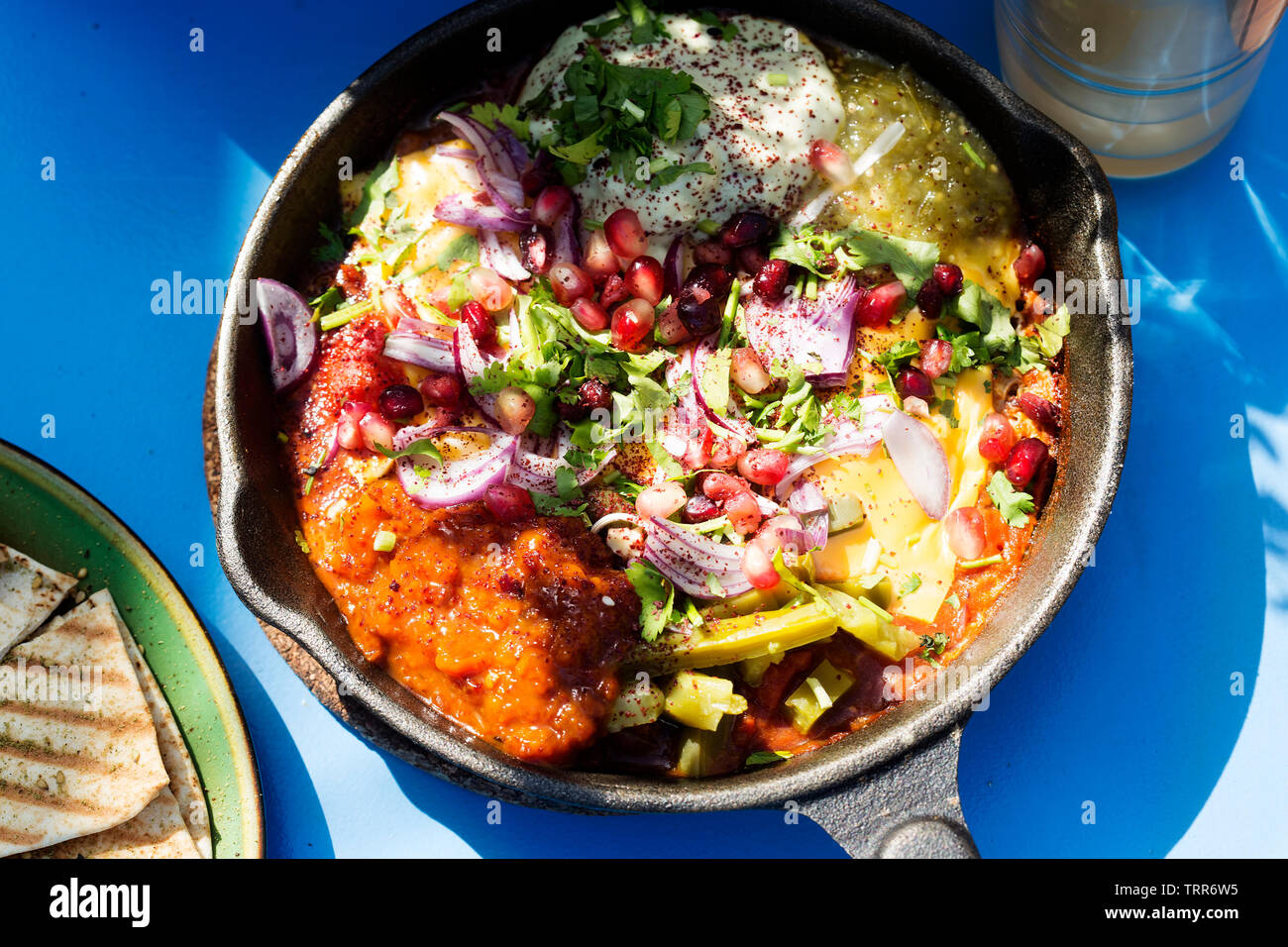 Shaksouka Hola Mexico. Eggs baked in aromatic tomato and peppers paste, with beans, served with marinated cactus, guacamole, salsa verde, salsa chipot Stock Photo