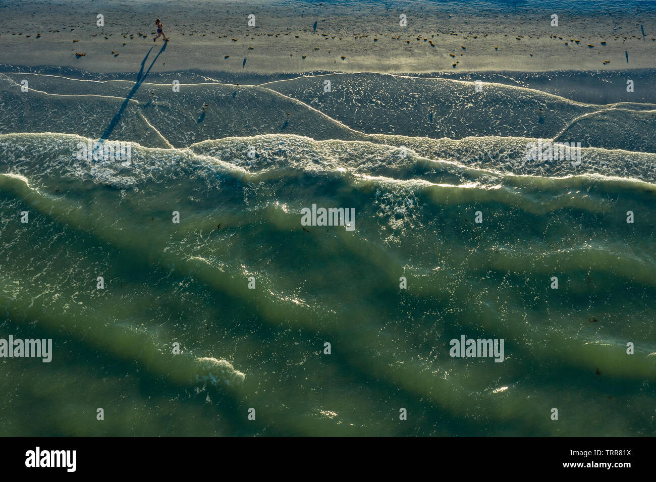 Ariel view of woman running along beach as waves roll in St. Pete Beach Florida. Stock Photo