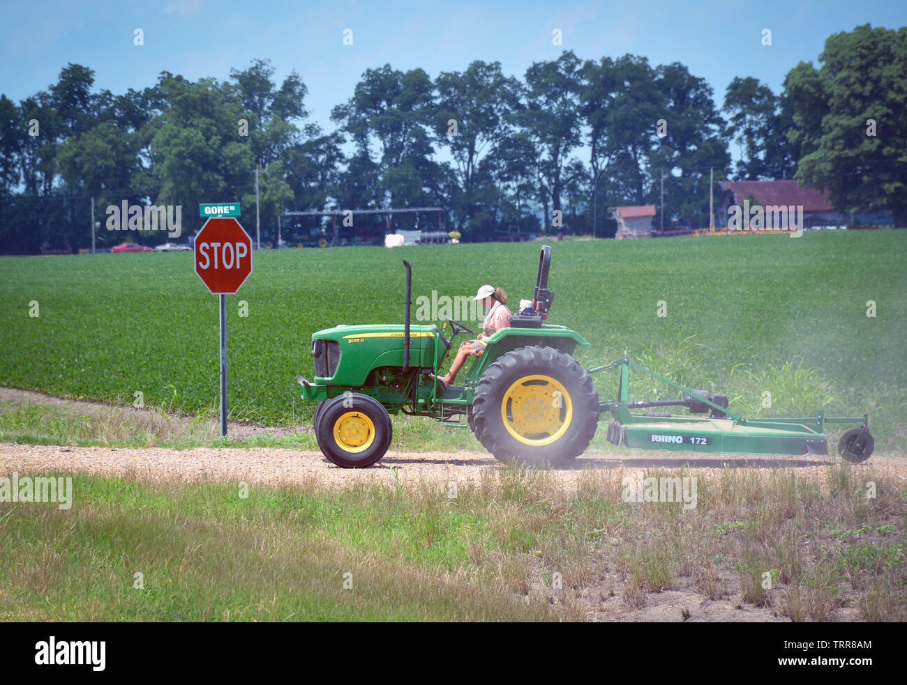 A woman driving a John Deere tractor with a utility mower attached