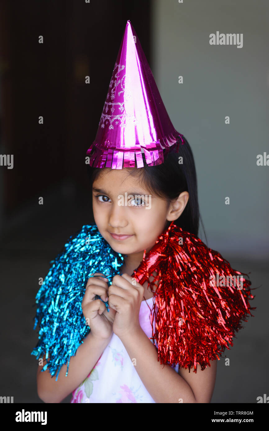 Portrait of a girl wearing party hat and holding pom pom Stock Photo