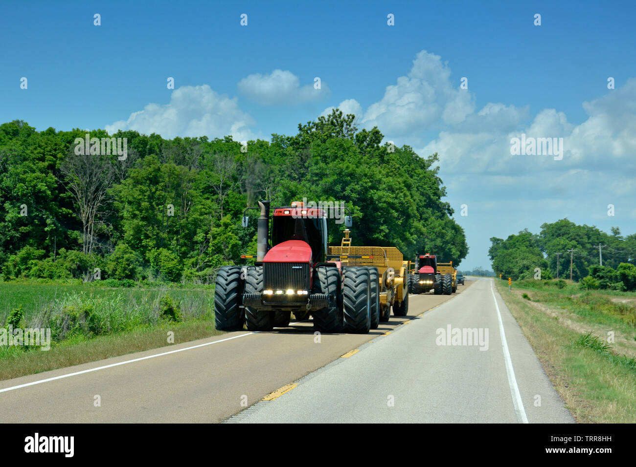 Two huge farm tractors are wide loads going down country highway in Northwestern Mississippi