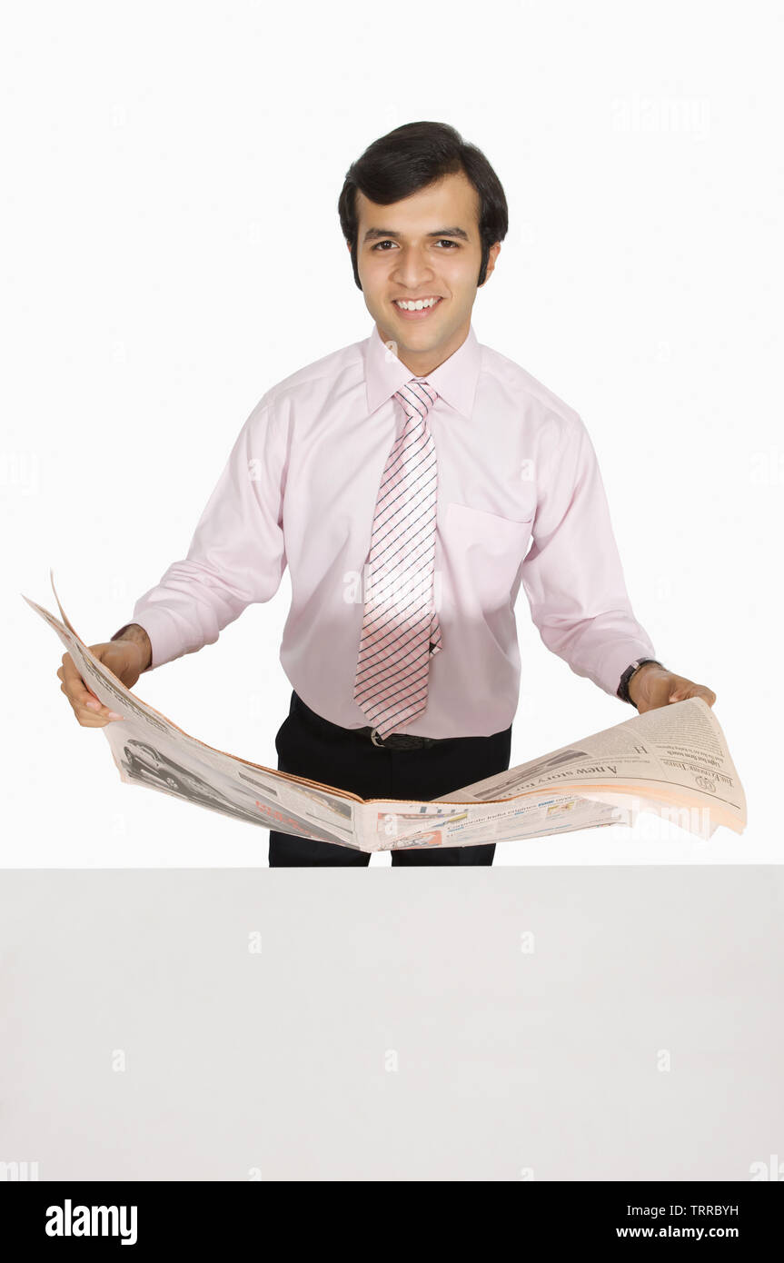 Businessman reading a newspaper and smiling Stock Photo - Alamy