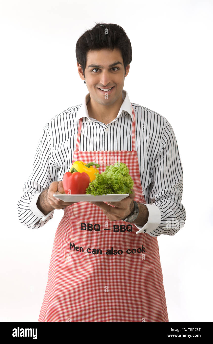 Man holding a plate of raw vegetables and smiling Stock Photo