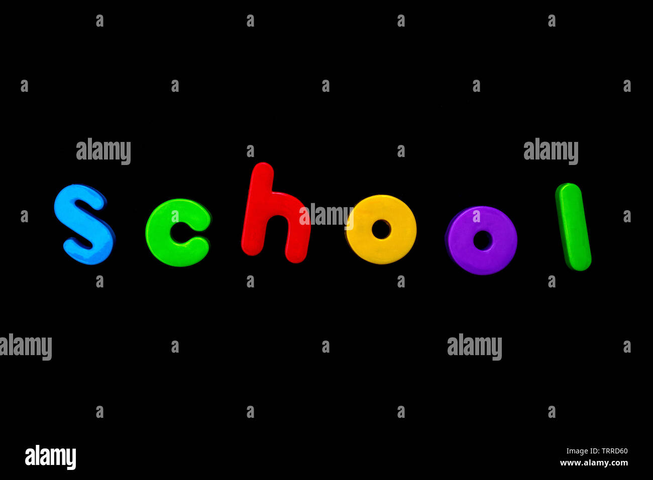 The word SCHOOL spelt with brightly coloured letters over a black background. Stock Photo