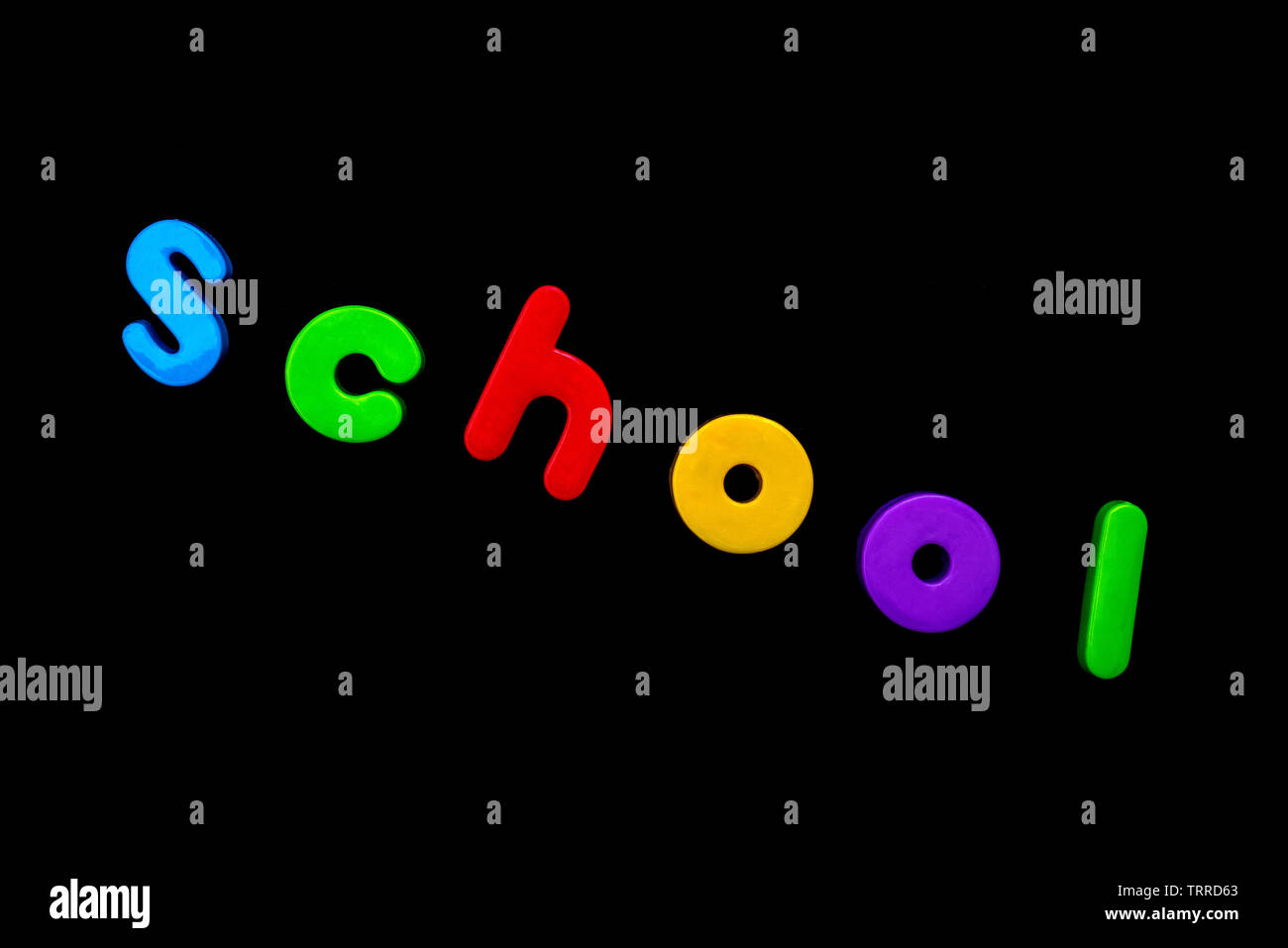 The word SCHOOL spelt with brightly coloured letters over a black background. Stock Photo