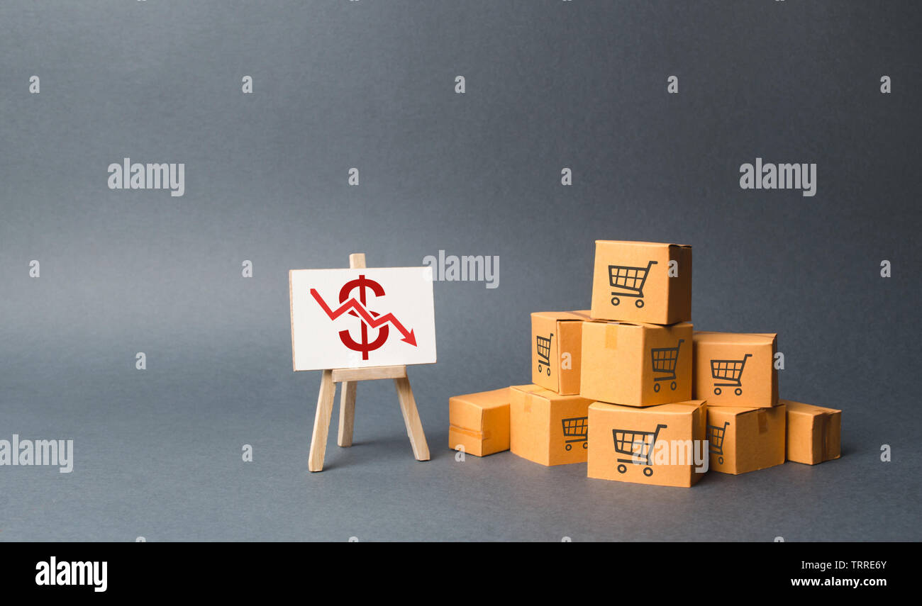A pile of cardboard boxes and stand with a red down arrow. decline in the production of goods and products, the economic downturn and recession. Falli Stock Photo