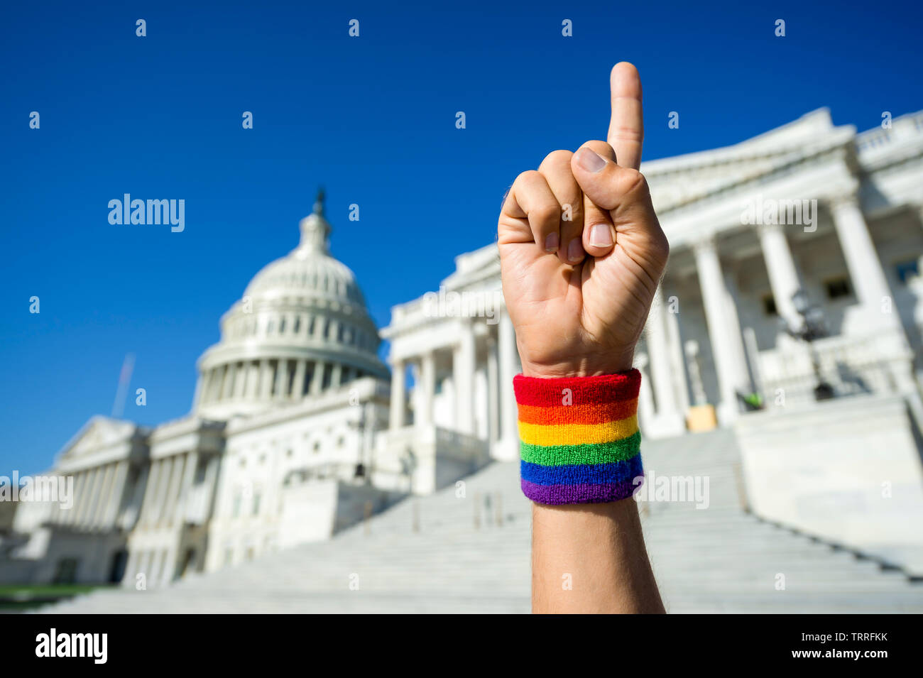 Hand wearing gay pride rainbow wristband holding up number one index finger outside the Capitol Building in Washington, DC, USA Stock Photo