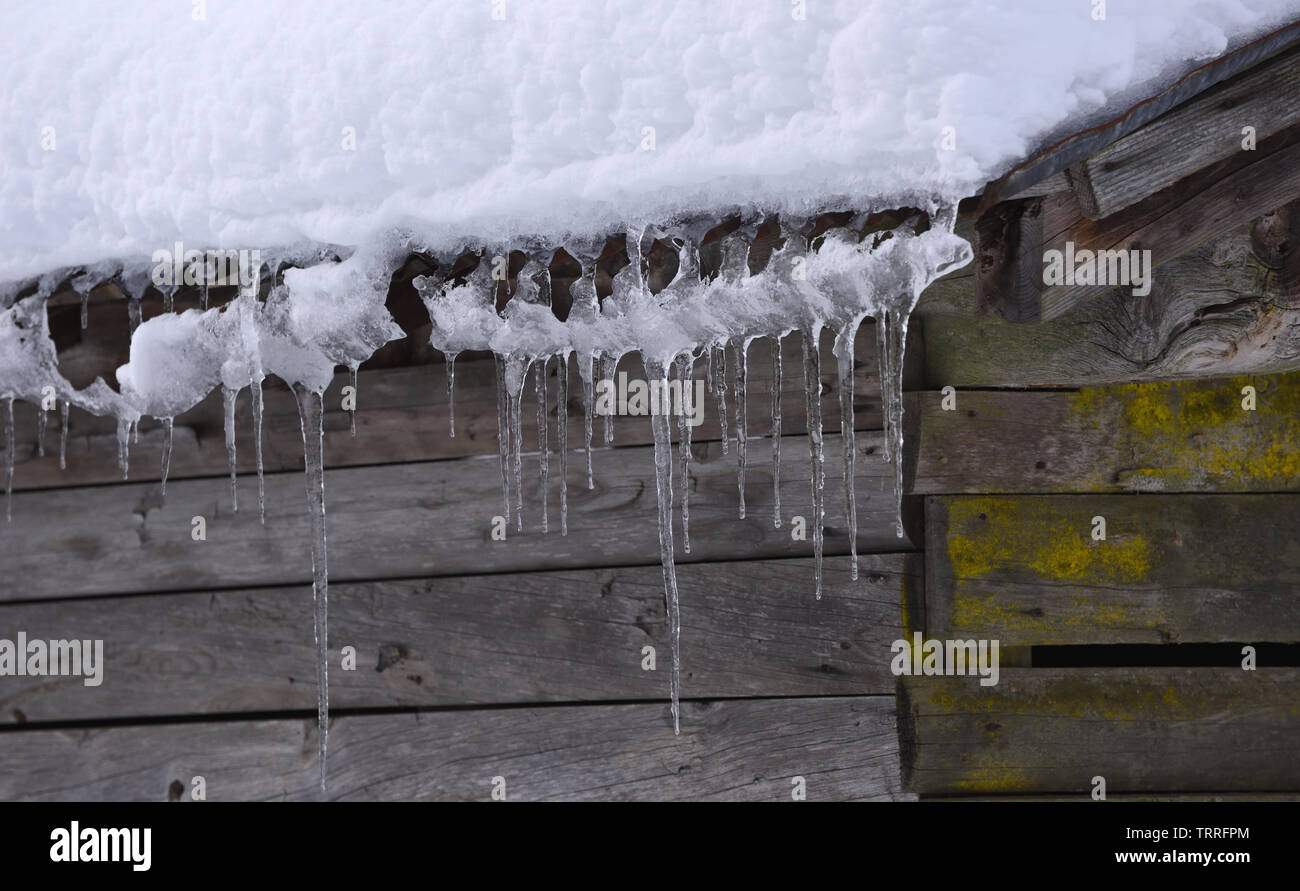 Icicles drip from the snow covered roof of a wooden hut. Samoens, Haute Savoie, France. Stock Photo
