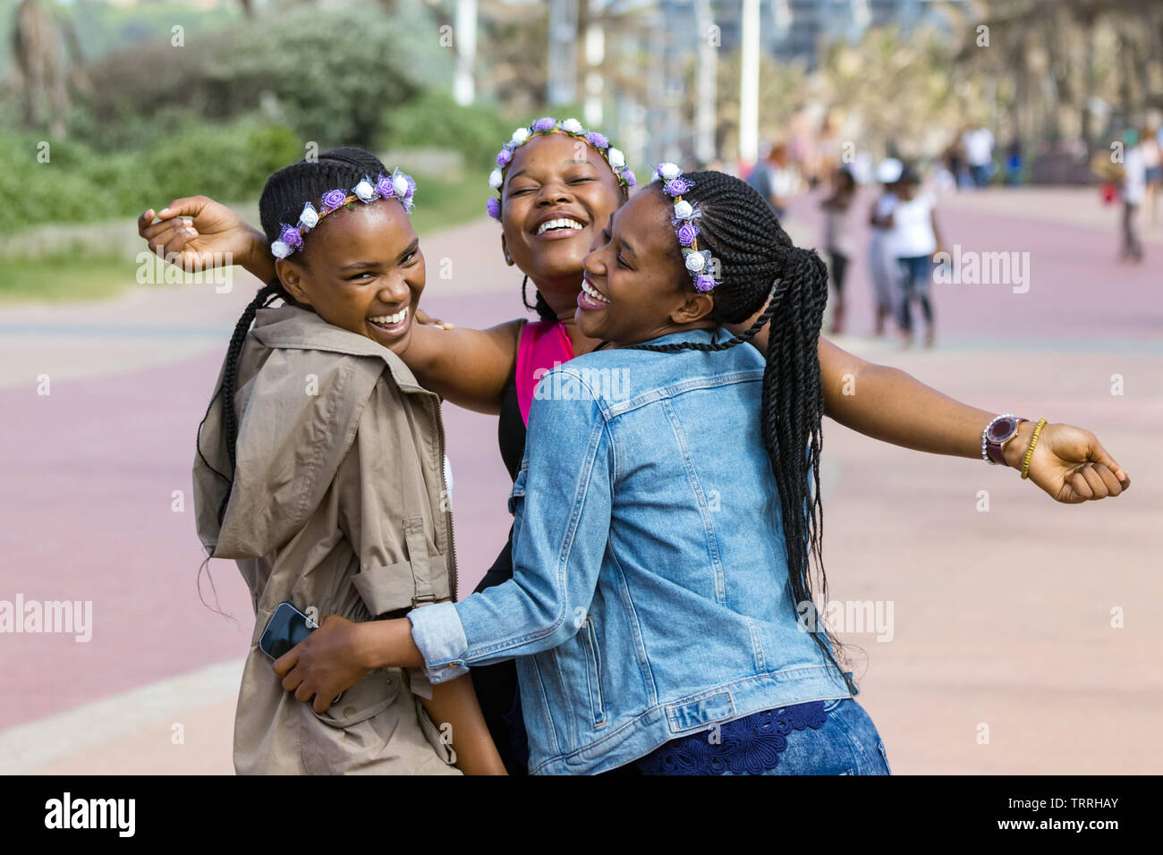 Three beautiful black young women laughing and celebrating friendship outdoors in South Africa. Stock Photo
