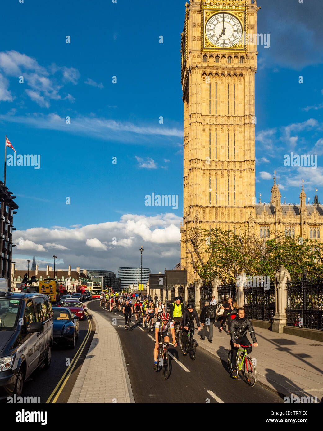 London, England - May 24, 2016: Cyclists pass the Big Ben clock tower of the Houses of Parliament on the nearly opened East-West Cycle Superhighway. Stock Photo