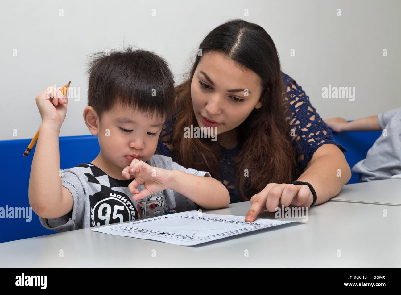 Manila, Philippines - August, 18, 2016: A female teacher teaching little boy, explaining how to write in classroom at school Stock Photo