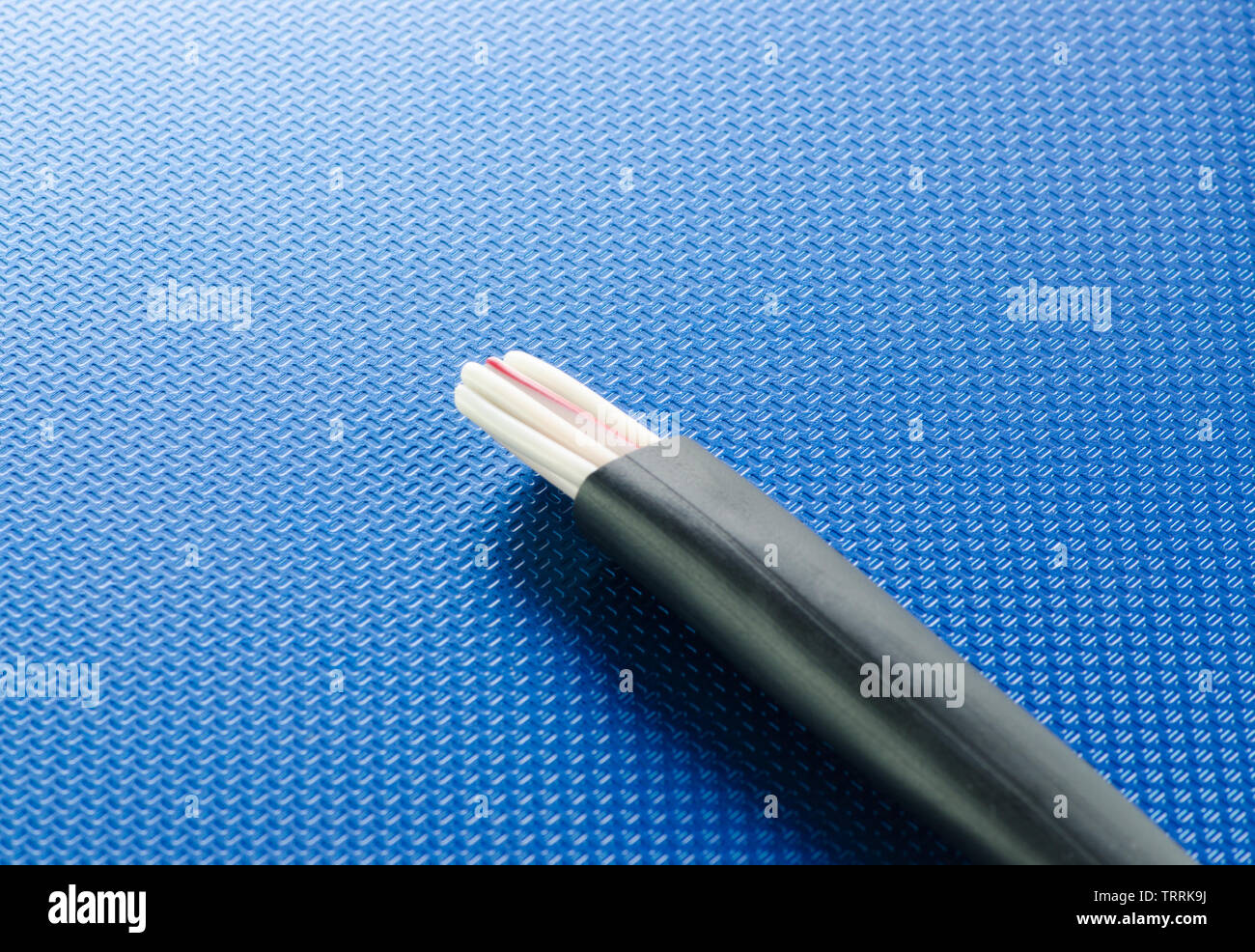Cross-section of control cable on blue ribbed technological background Stock Photo