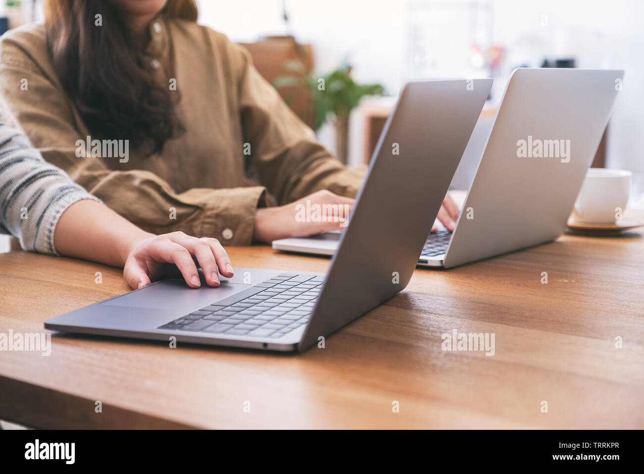 People using and looking at laptop computer on wooden table together Stock Photo