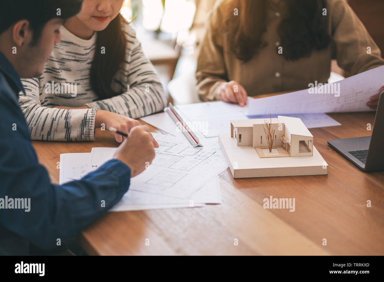 Group of an architect working and discussing about an architecture model together with shop drawing paper on table in office Stock Photo