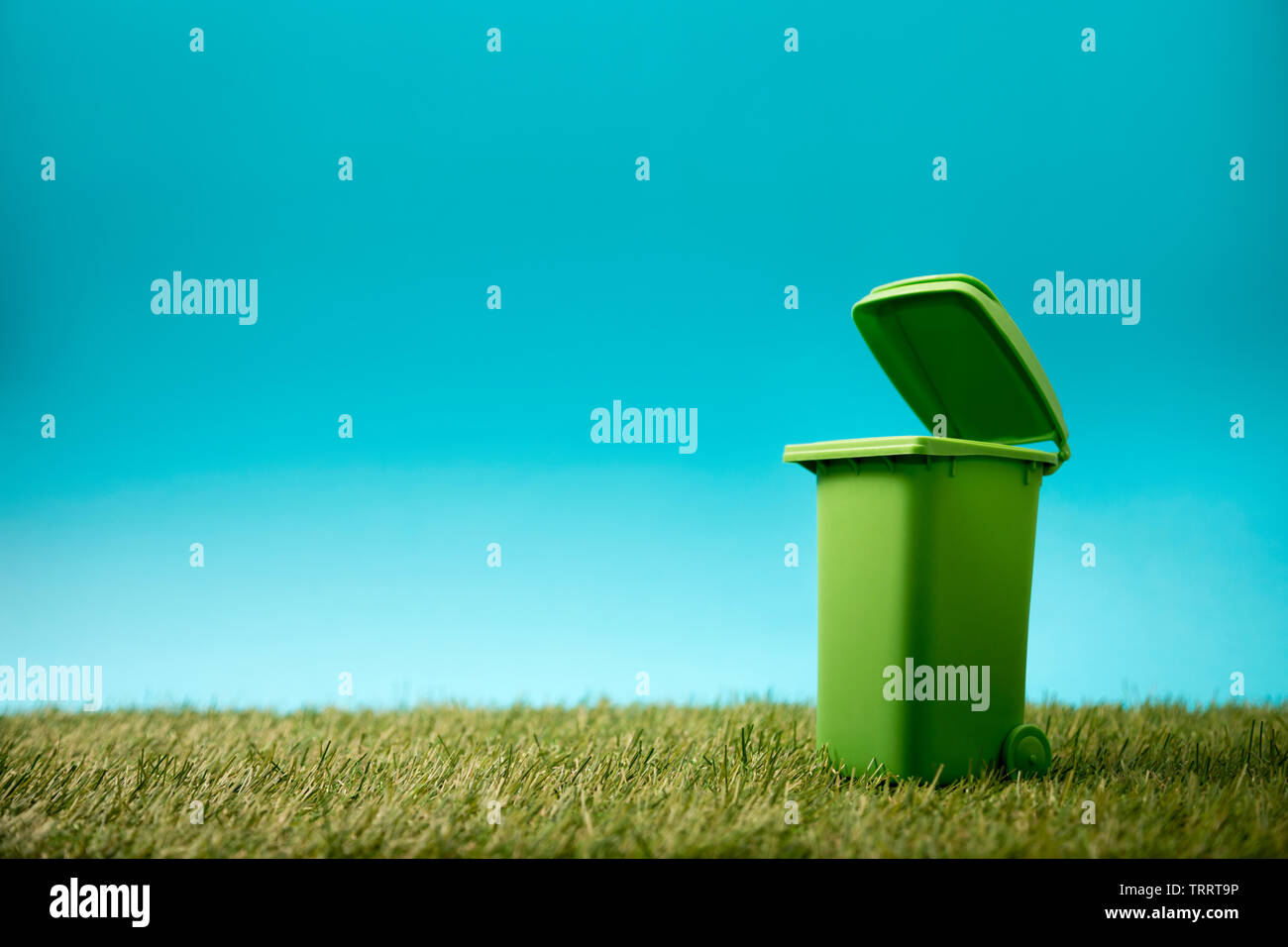 Green recycle bin on green grass and blue sky Stock Photo