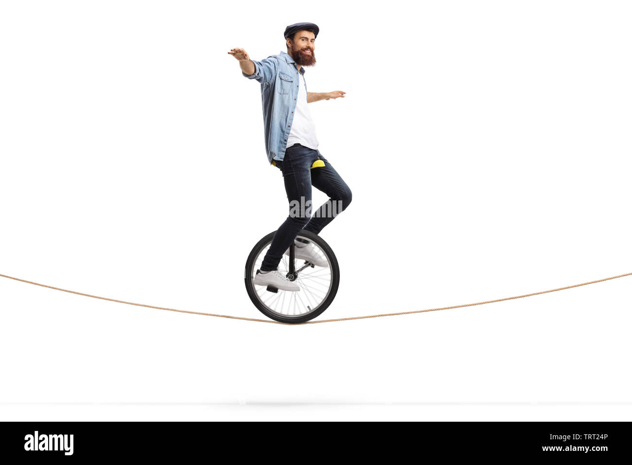 Full length shot of a man riding a unicycle on a rope and balancing with his hands isolated on white background Stock Photo