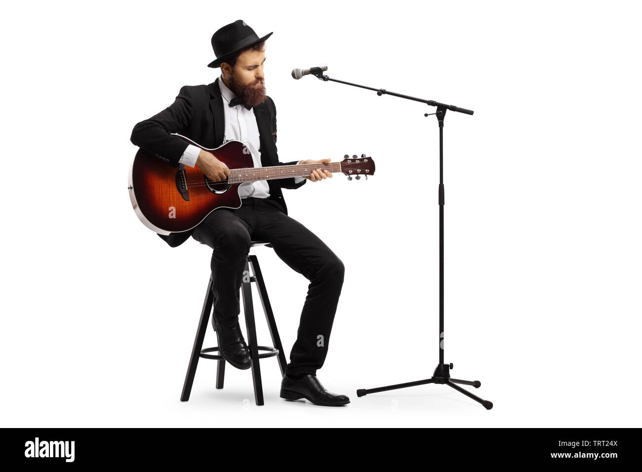 Full length shot of a man playing an acoustic guitar with a microphone in front of him isolated on white background Stock Photo