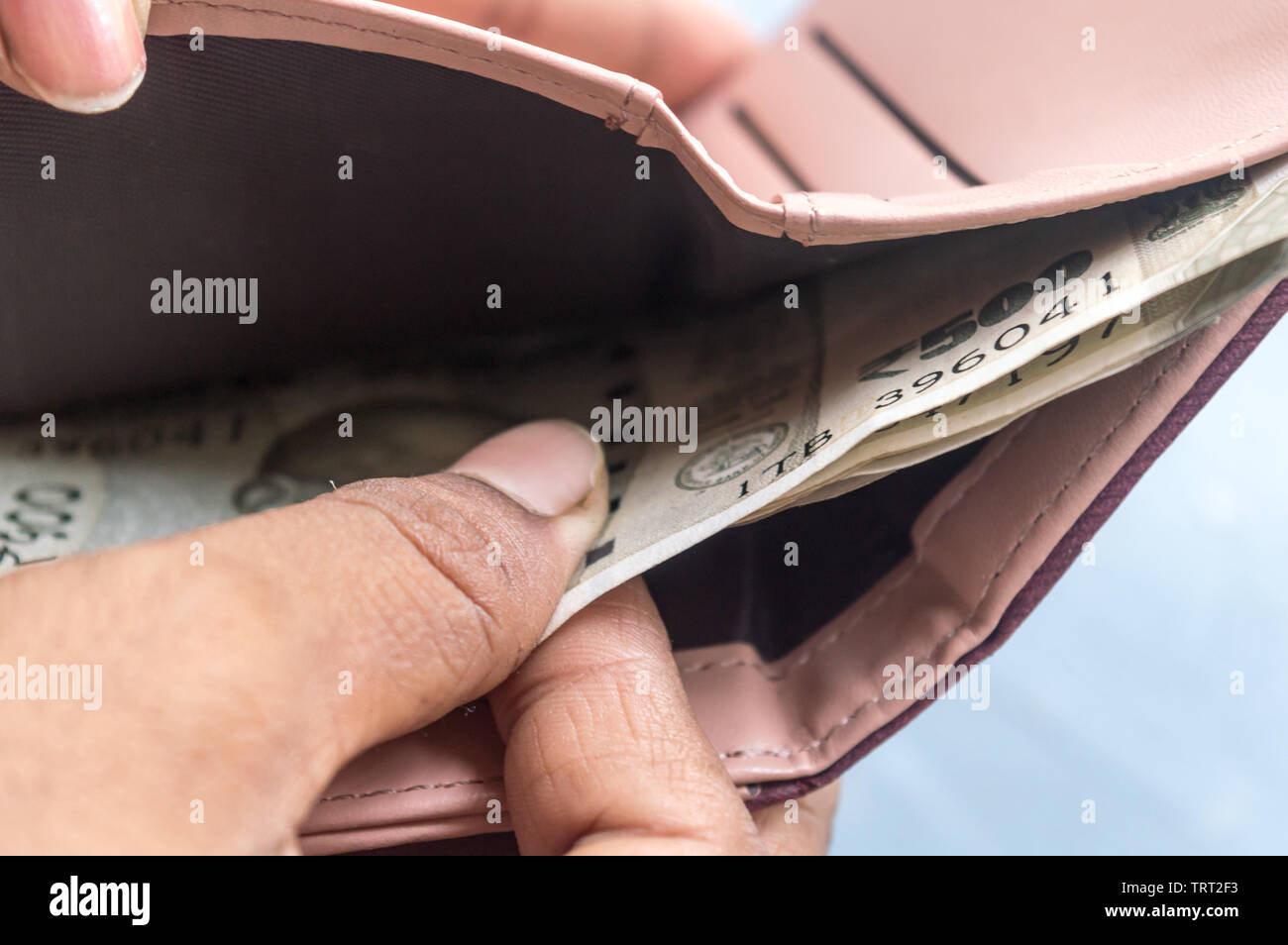 Businesswoman putting or taking out or paying Indian rupee banknotes from leather wallet. Isolated white background. Earning crisis growth bribe corru Stock Photo