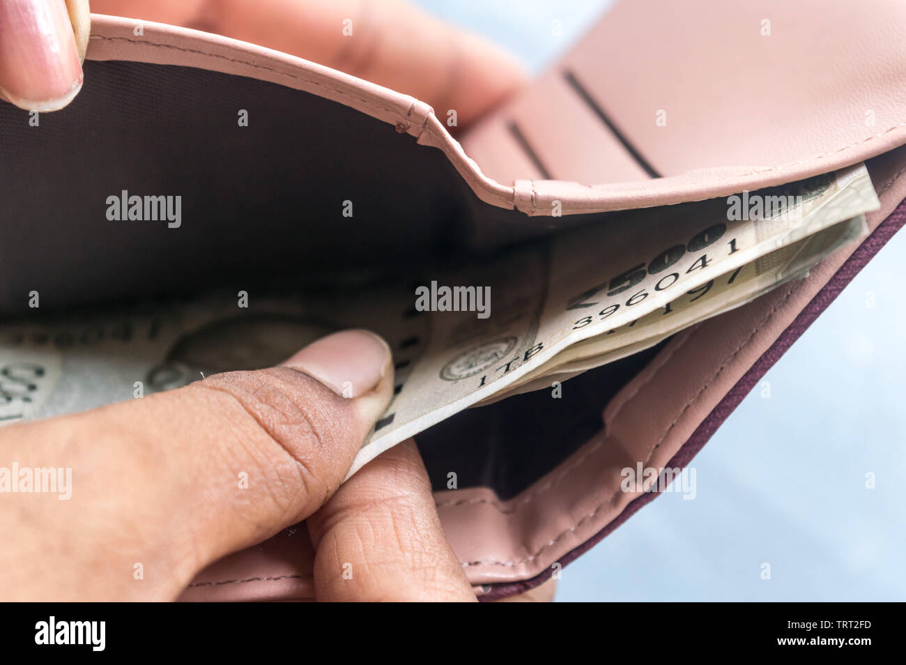 Businesswoman putting or taking out or paying Indian rupee banknotes from leather wallet. Isolated white background. Earning crisis growth bribe corru Stock Photo