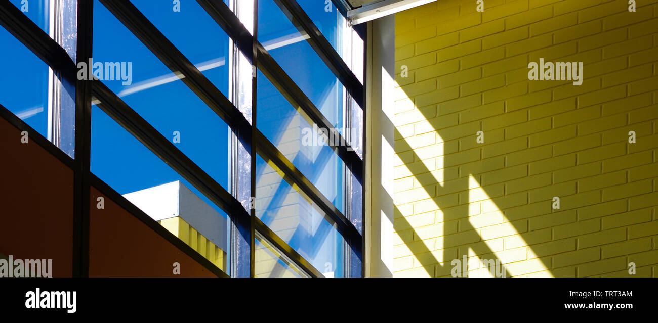 shadows of window frame on yellow brick wall with blue sky and sunlight banner Stock Photo