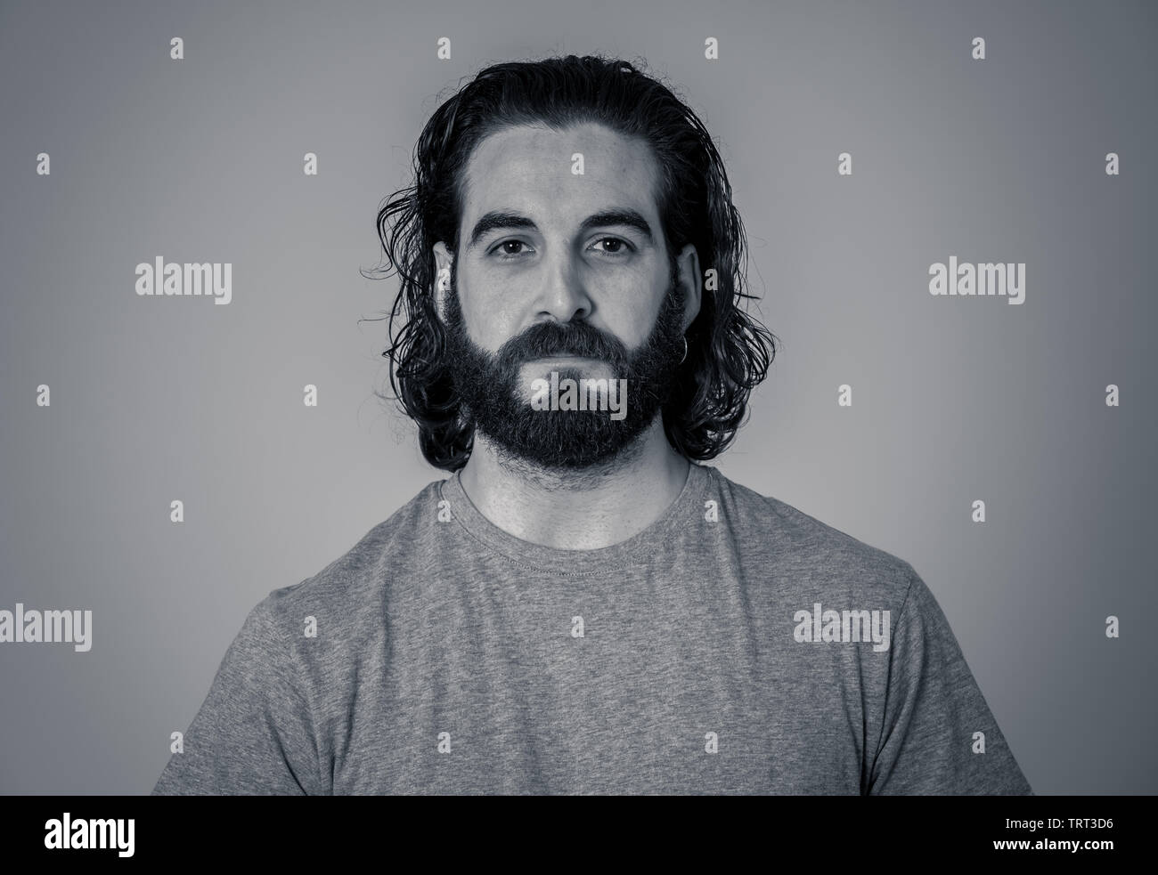 Close up headshot of young Hipster man with natural and neutral face with beard and long hair. Isolated on neutral background. In People, fashion, lif Stock Photo