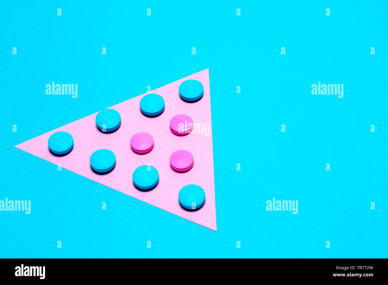 blue and pink tablets laid out in the form of a triangle or an arrow on a paper background of blue and pink. Medication and prescription pills minimal Stock Photo